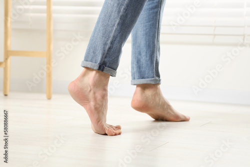 Barefoot man walking on white parquet indoors, closeup. Heated floor