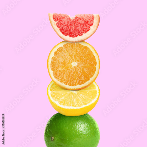 Stack of different fresh citrus fruits on pale pink background