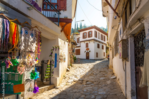 A narrow stone hillside alley with shops and homes in the ancient village of Sirince, Turkey.