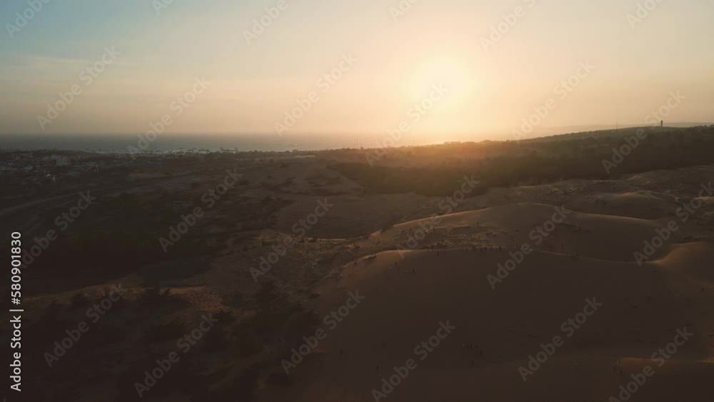 Scenic aerial pan over red dunes of Mui Ne at sunset, tourists exploring Scenic aerial pan over red dunes of Mui Ne at sunset, tourists exploring