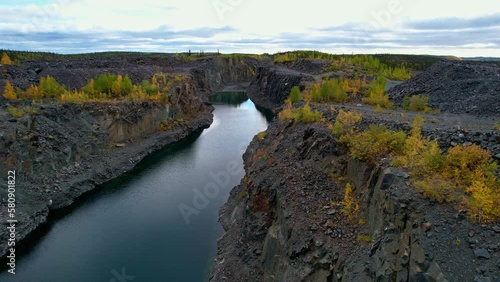 Aerial flyover of water-filled open pit mine excavation in a historical gold mine in northern Canada