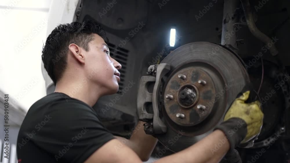 Slow motion shot of a car mechanic checking the brakes and pads on a car Slow motion shot of a car mechanic checking the brakes and pads on a car