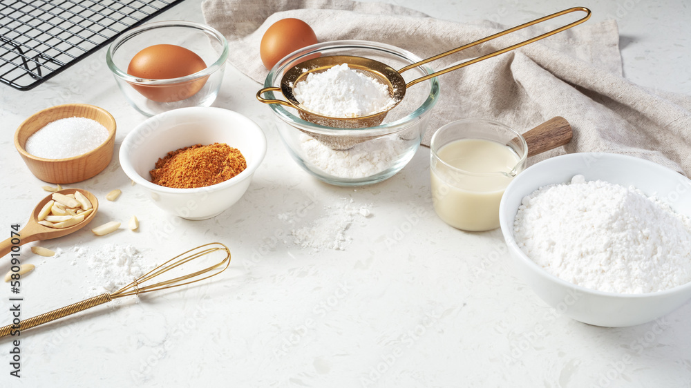 Baking background, pastry or cake ingredients, sifting flour, brown sugar, eggs and milk with utensil Baking background, pastry or cake ingredients, sifting flour, brown sugar, eggs and milk with utensil