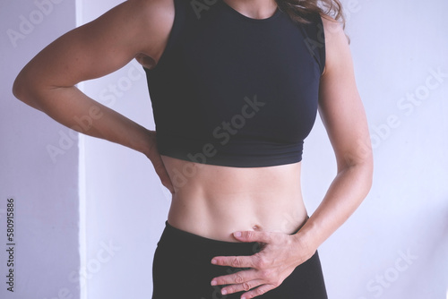 Woman toughing her back and stomach, person suffering from back and abdominal pain, backache, menstrual pain. Health care concept.