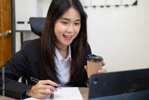 Close up portrait of a beautiful young Asia woman smiling and looking at laptop screen