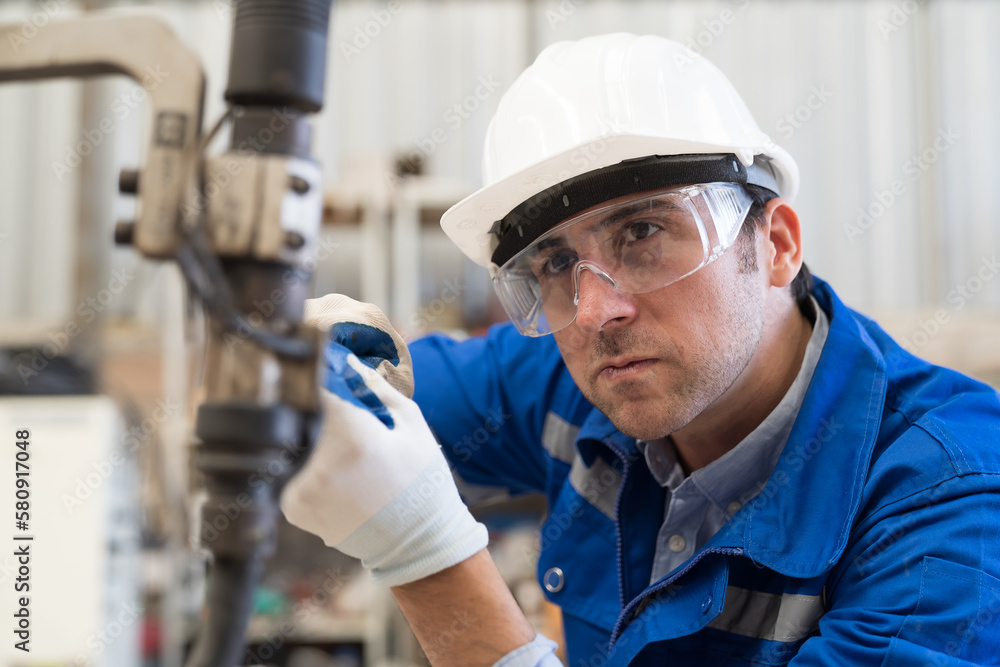 Male engineer maintenance automatic welding robotic arm machine in factory. Male technician worker checking, repair old robot arm machine in workshop Male engineer maintenance automatic welding robotic arm machine in factory. Male technician worker checking, repair old robot arm machine in workshop