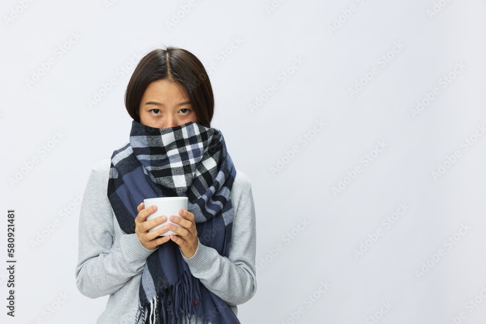Asian woman cold flu holding a mug of tea in plaid with fever is sick from the virus on a white background Asian woman cold flu holding a mug of tea in plaid with fever is sick from the virus on a white background