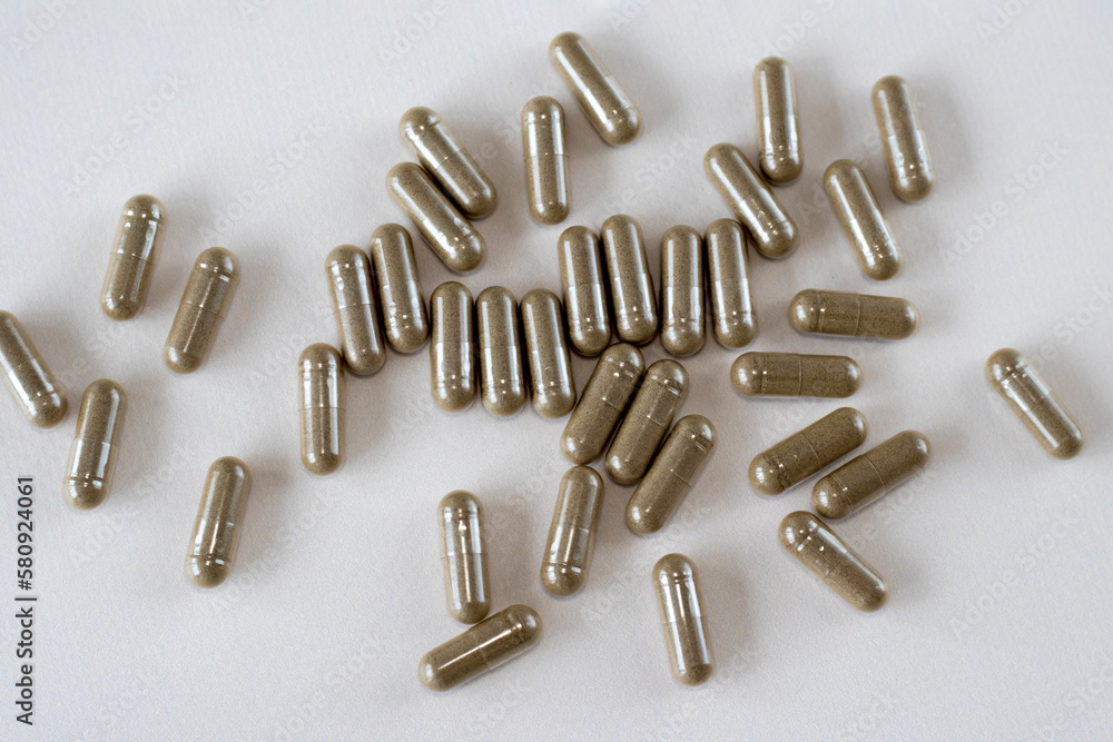 Gray-brown health capsules on a beige background. Dietary supplements and pills in a spoonful. Gray-brown health capsules on a beige background. Dietary supplements and pills in a spoonful.