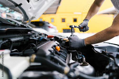 Professional car mechanic using a wrench for working on the engine of the car in the garage for car auto repair service and maintenance check concept for the car before leaving.