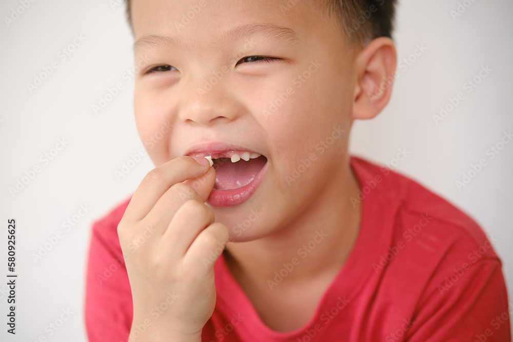 Cute Asian happy smiling schoolboy child showing missing teeth, Little kid losing his baby teeth and holding missing tooth, Dental care for children concept, Selective focus Cute Asian happy smiling schoolboy child showing missing teeth, Little kid losing his baby teeth and holding missing tooth, Dental care for children concept, Selective focus