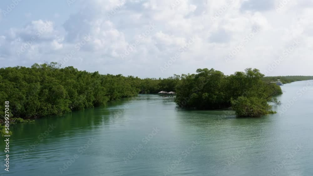 Dolly in aerial drone shot of a small secluded natural turquoise pool with thatch umbrella's branching from the Curimataú river near Barra de Cunhaú in Rio Grande do Norte, Brazil Dolly in aerial drone shot of a small secluded natural turquoise pool with thatch umbrella's branching from the Curimataú river near Barra de Cunhaú in Rio Grande do Norte, Brazil