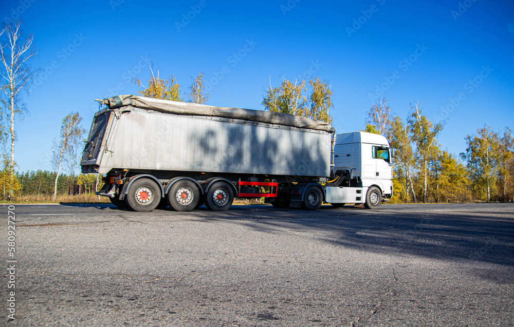 Transportation in special trailers of bulk cargoes of sand and coal on country roads. Automobile cargo transportation, industry. Copy space for text