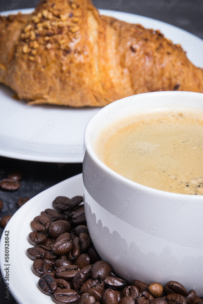 Breakfast consisting of fresh croissant with chocolate and coffee in white cup Breakfast consisting of fresh croissant with chocolate and coffee in white cup