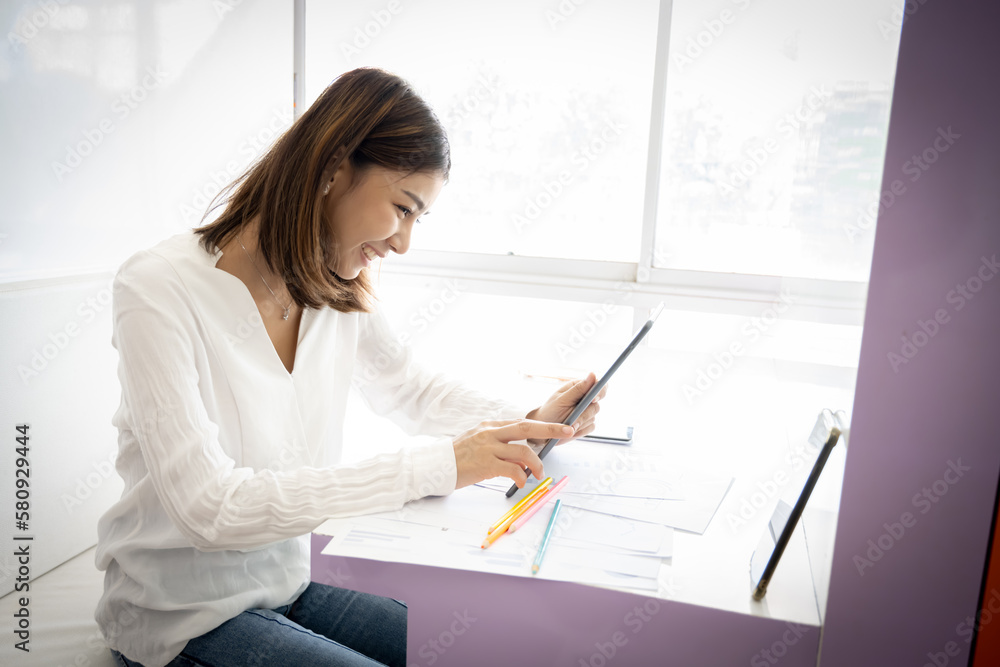 Beautiful asian businesswoman checking work on her tablet with smile in her office room. Beautiful asian businesswoman checking work on her tablet with smile in her office room.