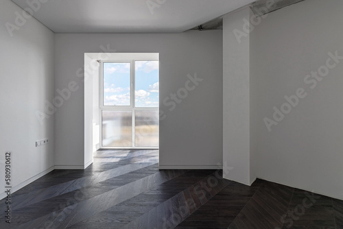 Empty apartment with large floor-to-floor window overlooking nature and blue sky with clouds
