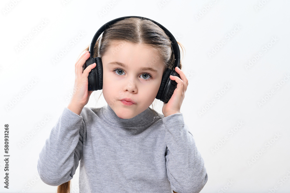 A child with headphones on a white background, a cheerful and beautiful girl with headphones. A child with headphones on a white background, a cheerful and beautiful girl with headphones.