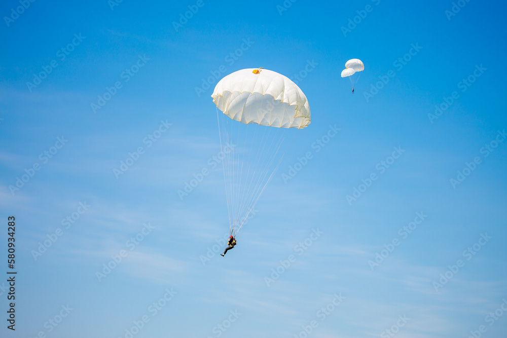 Skydiving. Flying parachutists against the background of the blue sky and mountains. Extreme sport and entertainment. Skydiving. Flying parachutists against the background of the blue sky and mountains. Extreme sport and entertainment.