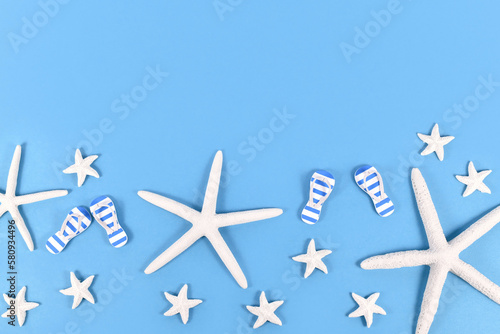 Summer shoes and starfish on blue background with copy space