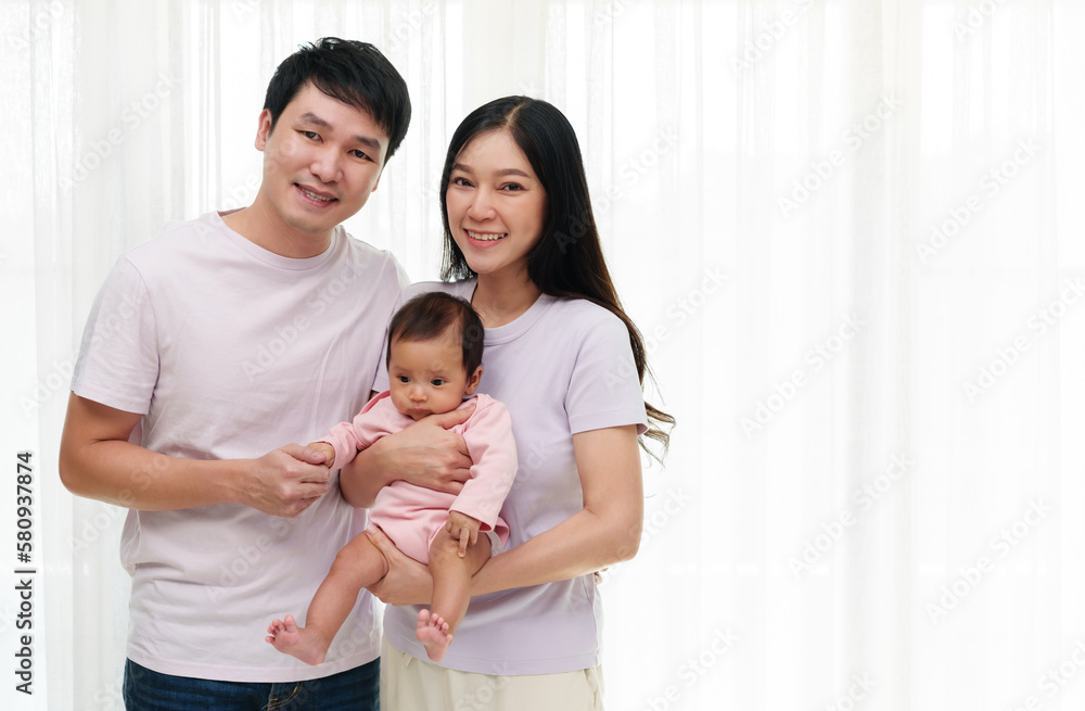 cheerful father and mother holding newborn baby on window background. happy family concept cheerful father and mother holding newborn baby on window background. happy family concept