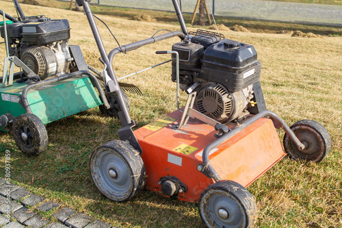 Two lawn mowers are parked on a green lawn in the park