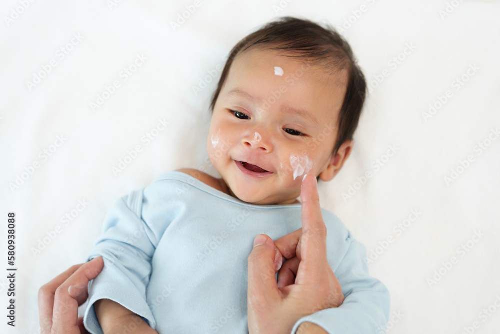 mother applying moisturizing cream on face of newborn baby mother applying moisturizing cream on face of newborn baby