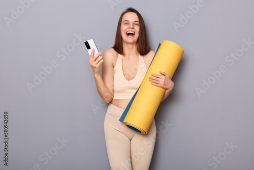 Papier peint Sporty woman with brown hair wearing sportswear with fitness mat in hands, stand