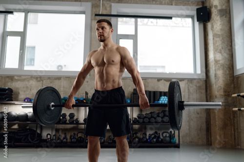 Handsome strong athletic man pumping muscle with barbell