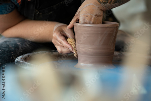 Hands crafting a pot on pottery wheel photo
