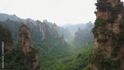 Surreal nature aerial: misty jungle valley amid tall rocky spires photo