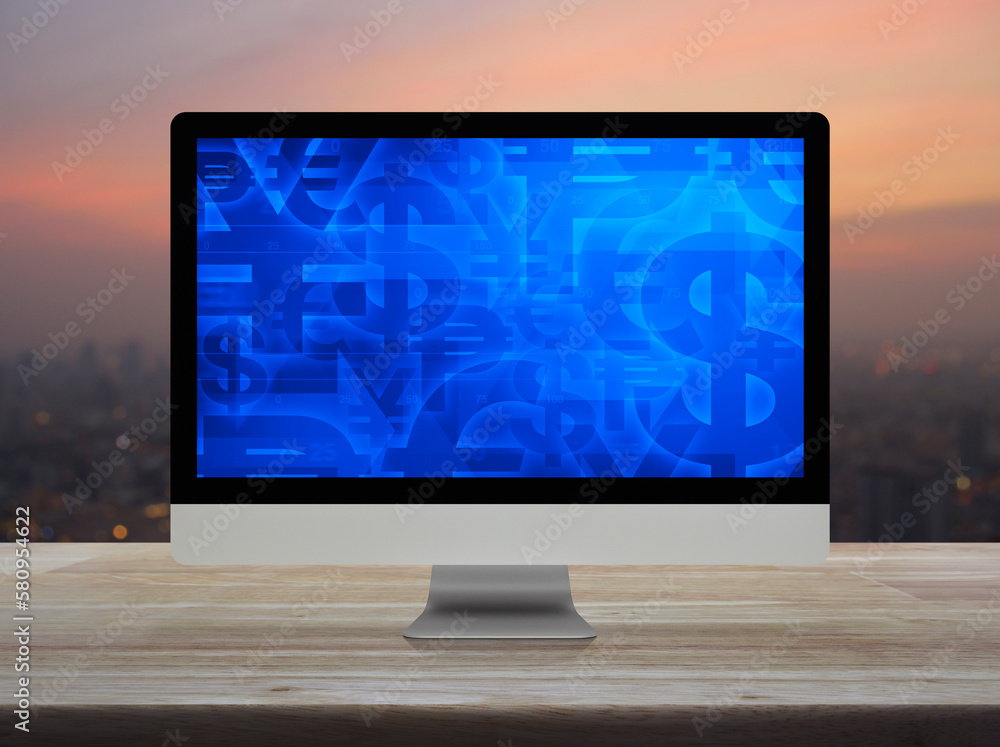 Fototapeta premium Financial currency symbol on desktop computer monitor screen on wooden table over blur of cityscape on warm light sundown