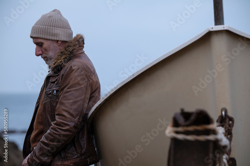 Adult man in leather jacket with a boat against sea and sky. Almeria, Spain
