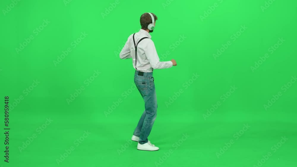 Passer-by cheerful man in a white shirt walks on a green background, dancing and listening to music with headphones, template on a chromakey. Passer-by cheerful man in a white shirt walks on a green background, dancing and listening to music with headphones, template on a chromakey.