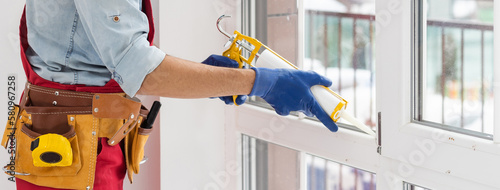 Принти на полотні Construction worker sealing window with caulk indoors