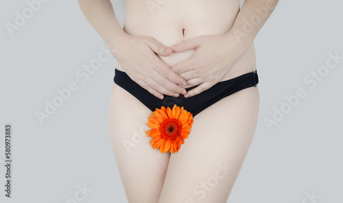 Virginity. Menstruation. Critical days. Concept photo. The girl holds a flower in the crotch area, symbolizing the hymen, critical days and gynecological problems.