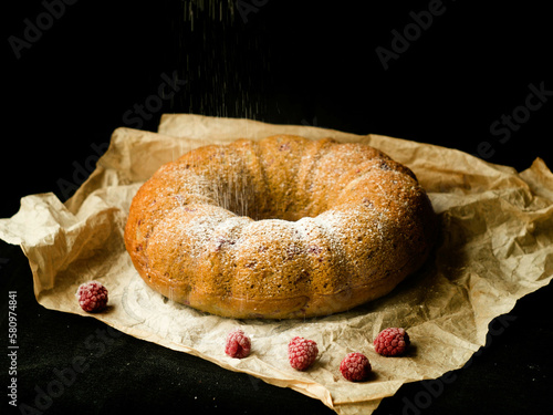 Vanilla bundt cake with fresh raspberries on a black table. vegetarian, lean, dairy and egg free. Selective focus. Close up
