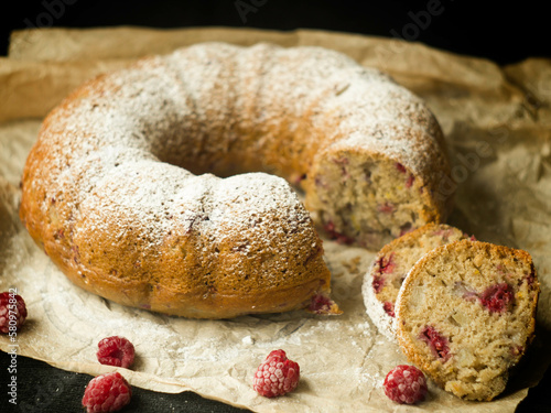Vanilla bundt cake with fresh raspberries on a black table. vegetarian, lean, dairy and egg free. Selective focus. Close up