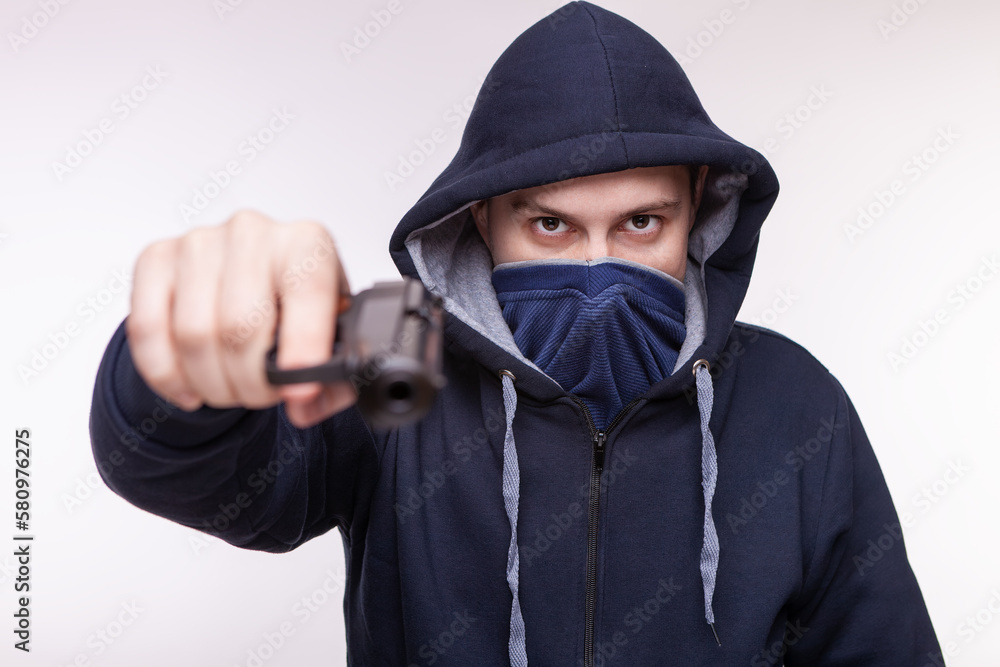 A man with a gun. Aggressive man in a mask and a gun. The criminal threatens with a gun A man with a gun. Aggressive man in a mask and a gun. The criminal threatens with a gun