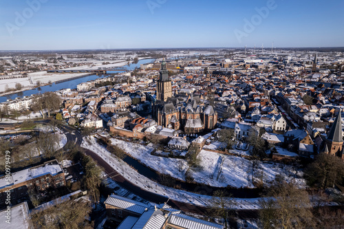 Picturesque winter wonderland aerial of medieval Hanseatic Dutch tower town Zutphen in the Netherlands covered in snow with historic heritage buildings and river IJssel passing by in the background photo