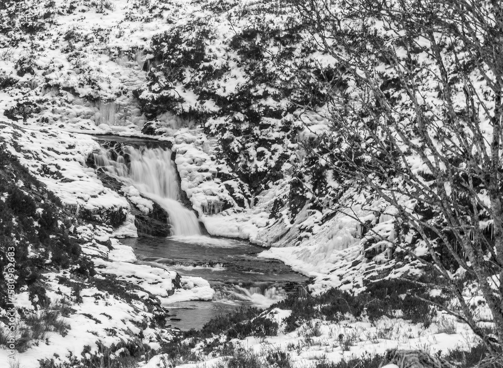 black and white background of a waterfall in a valley in the remote Scottish highlands in the snow