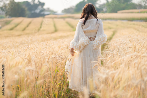 Beautiful Asian women were in white dresses relaxed and happy in the Barley rice field season golden color of the wheat plant. Freedom traveler, dreamy portrait in a wheat field.