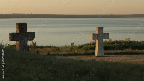 Stone crosses on the background of the Dnieper River at sunrise in the south of Ukraine, tradition and cultural heritage of the Zaporozhian Cossacks photo