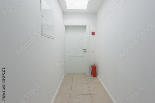 Apartment door at the end of the corridor with fire extinguisher
