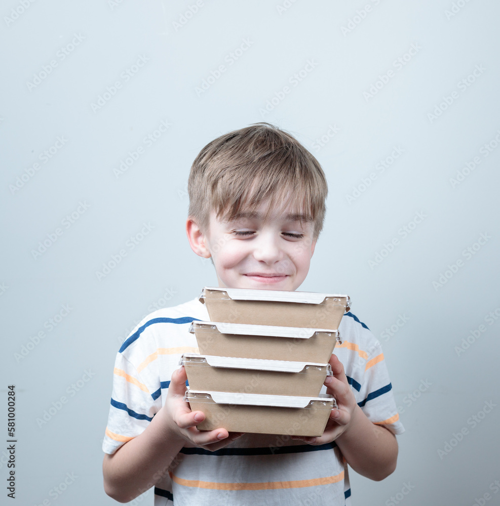 blond-haired boy holding containers of food. Food delivery, homemade meals. blond-haired boy holding containers of food. Food delivery, homemade meals.
