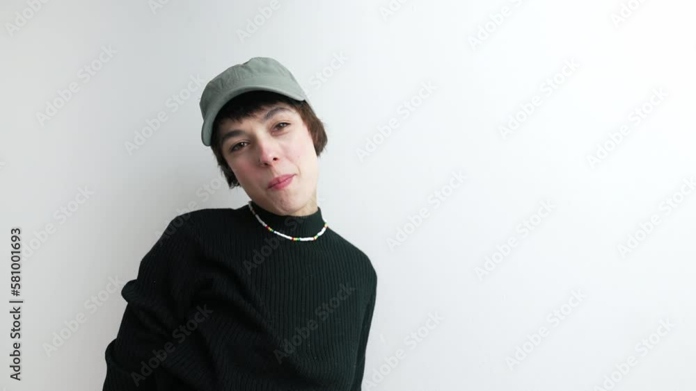 Headwear concept. Young adult woman in grey baseball hat posing in studio. Camera going down after focusing on model. High quality 4k footage Headwear concept. Young adult woman in grey baseball hat posing in studio. Camera going down after focusing on model. High quality 4k footage