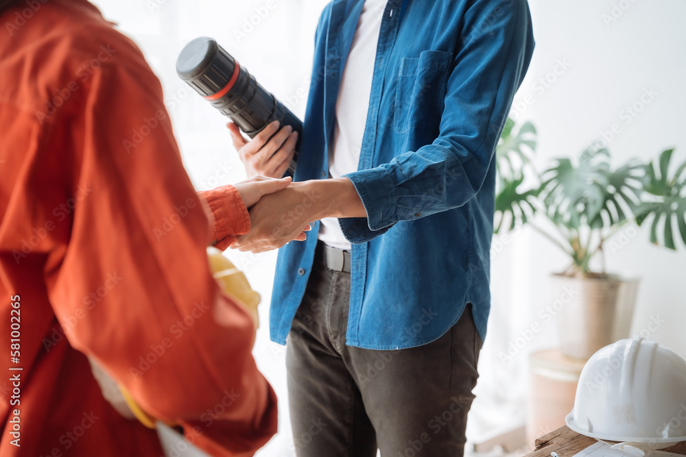 Fototapeta premium Young couple asian architects shake hands while working for teamwork, successful cooperation concept.