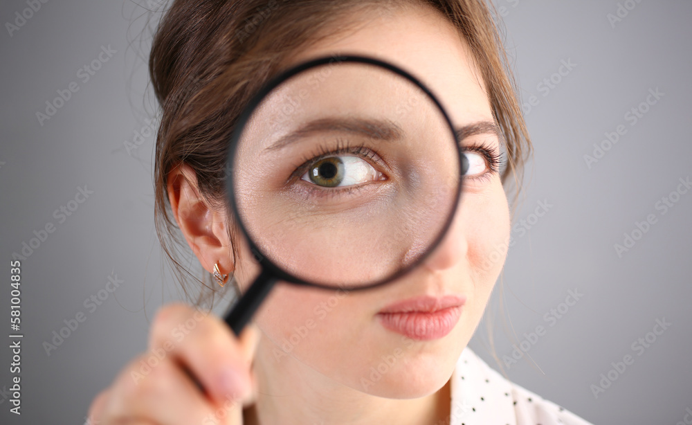 Inquisitive young woman looking through magnifying glass Inquisitive young woman looking through magnifying glass