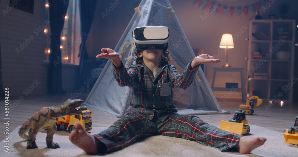 Foto de Little boy with curly hair wearing pyjamas is playing video