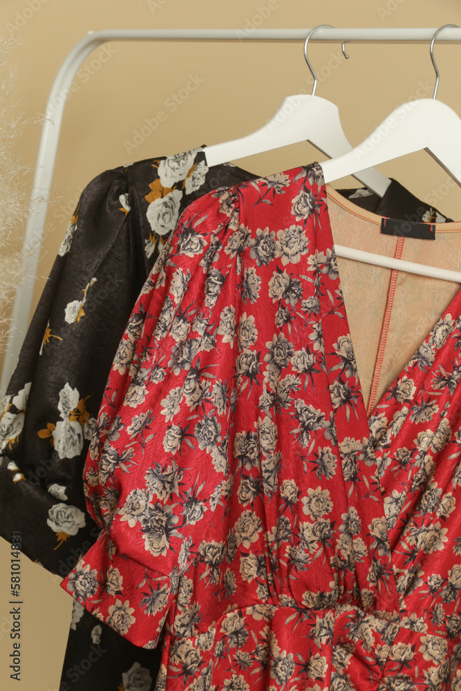 Naklejka premium Women's Clothes. Clothes rack with stylish and elegant floral silk dresses in fashion atelier. Good quality timeless fashion pieces. 