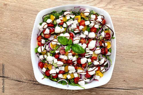 Vegetable salad on a white plate consisting of vegetables, cheese and balsamic dressing.