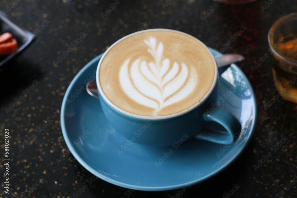 A cup of cappuccino served on an artistic black table A cup of cappuccino served on an artistic black table